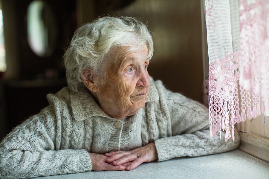 An elderly old woman looks sadly out the window. Care for lonely